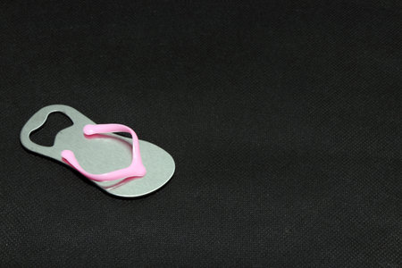 Metal bottle opener, design shape of slipper with pink clipping line on black background. it is a...
