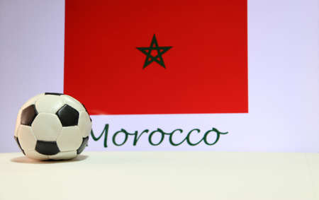 Small football on the white floor and Moroccan nation flag with the text of Morocco background. The concept of sport.の写真素材