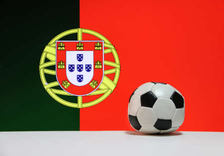 Small football on the white floor and Portuguese nation flag background. The concept of sport.の写真素材