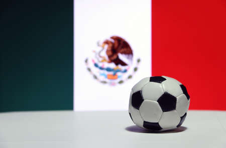 Small football on the white floor and Mexican nation flag with green white and red background. The concept of sport.の写真素材