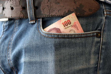 One hundred banknote of Thailand in the pocket of blue jeans.の写真素材