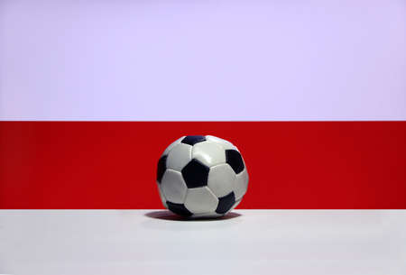 Small football on the white floor and Polish nation flag with white and red background. The concept of sport.の写真素材