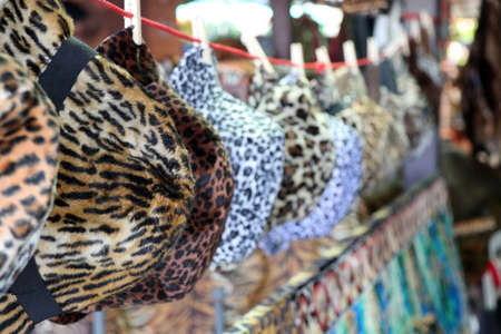 Tiger pattern fabric of cap and hat hanging on the line for sale in the local market.の写真素材