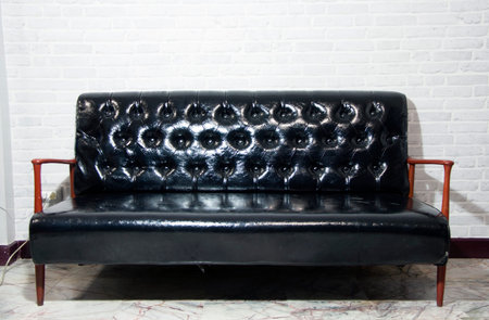 Black leather sofa and wooden armrest chair with gray background, Retro armchair decorate in the...