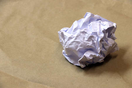 White crumpled paper ball on the brown paper floor.の写真素材