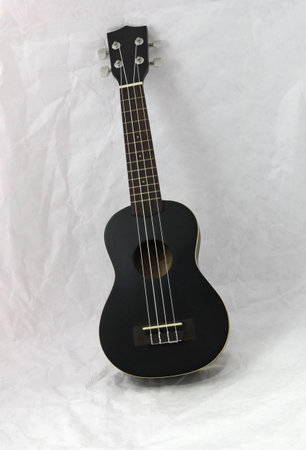 Black ukulele on the white background. it is a small four-stringed guitar of Hawaiian origin.