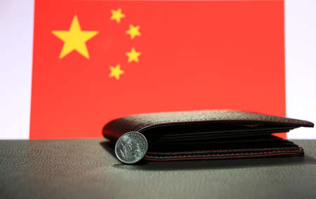 Chinese one Yuan coins on obverse (CNY) on black floor with black wallet and China flag background, the concept of finance.の写真素材
