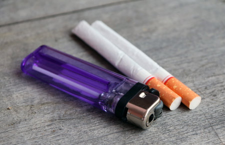 Thailand violet lighter and two cigarettes on the wooden table. cigarette is a thin cylinder of...