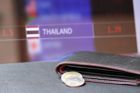 Pile of Thai baht coins on (THB) on black wallet with black floor and digital board of currency...