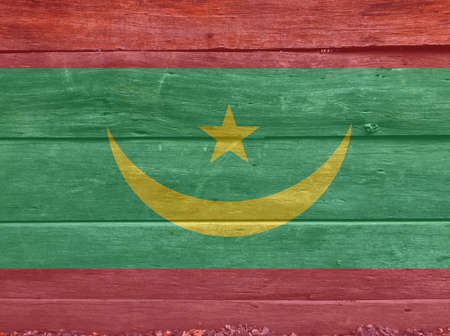 Flag of Mauritania on wooden wall background. Grunge Mauritania flag texture, Two red stripes flanking a green field with a golden crescent and star.の写真素材