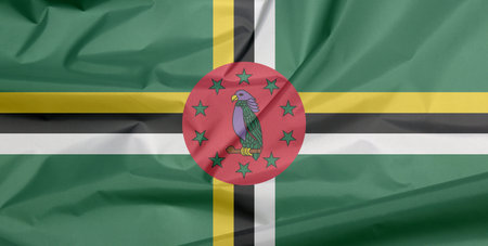 Fabric flag of Dominica. Crease of Domincian flag background, A green field with cross of yellow,...