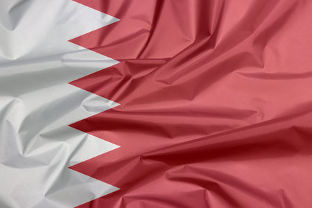 Fabric flag of Bahrain. Crease of Bahraini flag background, five white triangles in the form of...