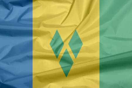 Fabric flag of Saint Vincent. Crease of Saint Vincent flag background, blue gold and green with three green diamonds arranged in the V.の写真素材