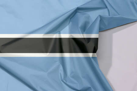 Botswana fabric flag crepe and crease with white space, black stripe with a thin white frame on light blue.の写真素材