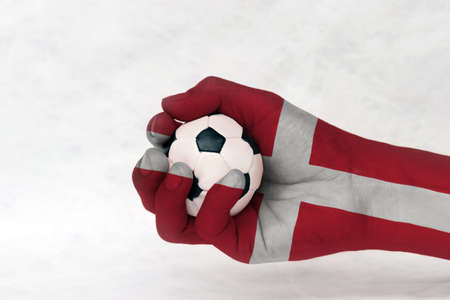 Mini ball of football in Denmark flag painted hand on white background. Concept of sport or the game in handle or minor matter.の写真素材