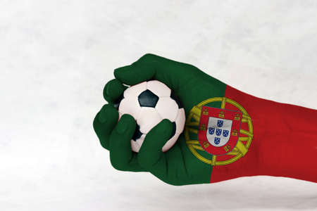 Mini ball of football in Portugal flag painted hand on white background. Concept of sport or the game in handle or minor matter.の写真素材