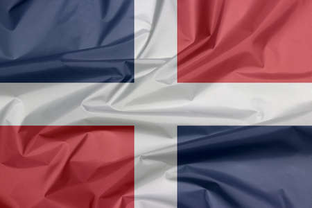 Fabric flag of Dominican. Crease of Dominican flag background, A white cross into four rectangles, blue and red at the top and red and blue at the bottom.の写真素材
