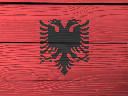 Flag of Albania on wooden wall background. Grunge Albanian flag texture, a red field with the black double-headed eagle in the center.の写真素材