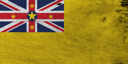 Flag of Niue on wooden plate background. Grunge Niue flag texture. A golden yellow flag with the Union Jack in the upper left with star.の写真素材
