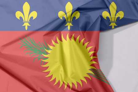 Guadeloupe Local fabric flag crepe and crease with white space, red field with yellow sun and green sugar cane, and a blue stripe with yellow fleurs-de-lis on the top.の写真素材