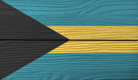Flag of Bahamas on wooden wall background. Grunge Bahamas flag texture, a horizontal triband of aquamarine (top and bottom) and gold with the black chevron aligned to the hoist-sideの写真素材