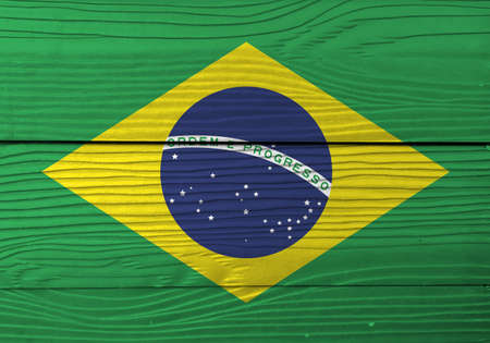 Flag of Brazil on wooden wall background. Grunge Brazil flag texture, green yellow and blue color and world in center.の写真素材