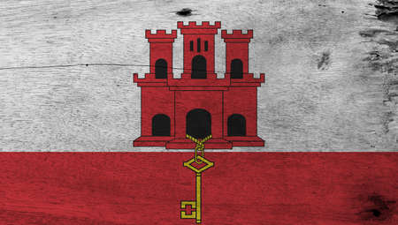 Flag of Gibraltar on wooden plate background. Grunge Gibraltar flag texture, White and red stripe with three towered and hangs a gold key.の写真素材