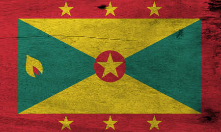 Flag of Grenada on wooden plate background. Grunge Grenadian flag texture, red border with six Gold star, Gold and green triangles with red disk.の写真素材