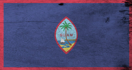 Flag of Guam on wooden plate background. Grunge Guam flag texture, dark blue background with a thin red border and the Seal of Guam.の写真素材