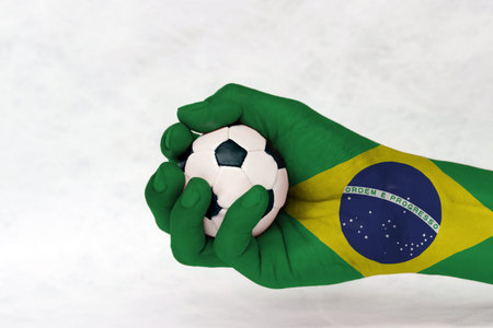 Mini ball of football in Brazil flag painted hand on white background. Concept of sport or the game in handle or minor matter. green yellow and blue color and world in center.の写真素材