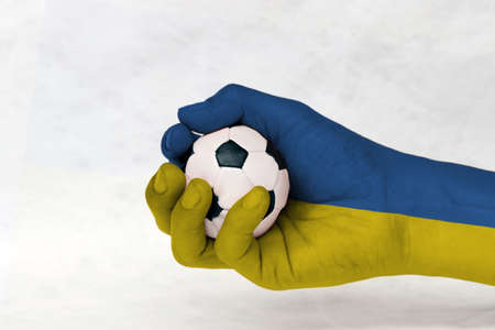 Mini ball of football in Ukraine flag painted hand on white background. Concept of sport or the game in handle or minor matter. horizontal bands of blue and yellow.の写真素材