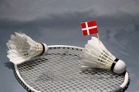 Mini Denmark flag stick on the shuttlecock put on the net of badminton racket and a shuttlecock on the grey floor.の写真素材