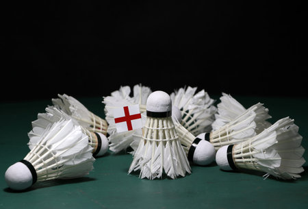 Mini England flag stick on the heap of used shuttlecocks on green floor of Badminton court with dark black background.の写真素材