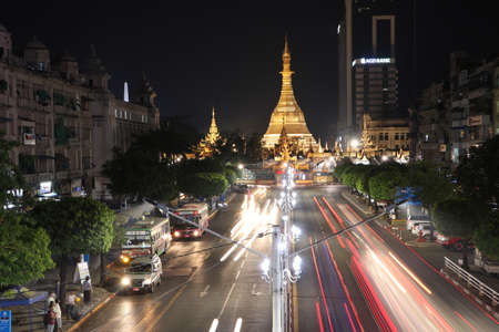 Yangon, Myanmar Feb 21, 2019: Night time and speed of light at golden octagon of Sula pagoda located in the heart of downtown Yangon with building and many cars on the junction of Sule Pagoda road.のeditorial素材