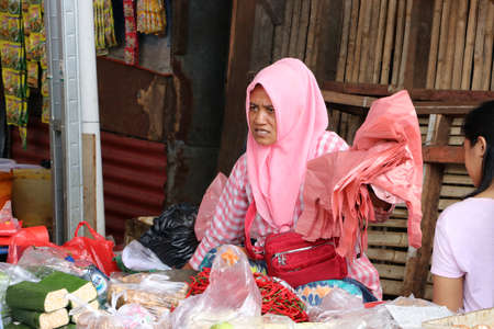 Jakarta, Indonesia May 6, 2019: Indonesian muslim women vegetable seller wearing a veil and selling vegetable in the market at Muara Angke harbor.のeditorial素材