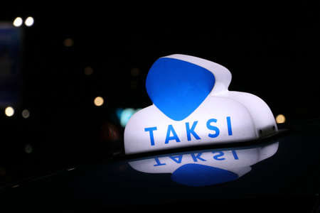 Taxi light sign or cab sign in blue and white color on the car roof at the street in the dark night, With text TAKSI in Indonesia.の写真素材