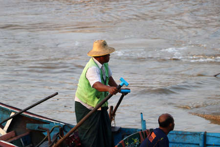 Yangon, Myanmar, Feb 25, 2019: Myanmar traditional ferry driver rowing to wait for passengers come to the ferry for across Yangon river on the morning.のeditorial素材