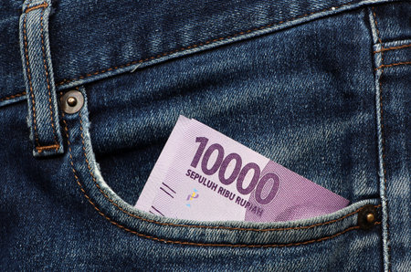 Banknote money ten thousand Indonesia Rupiah in the pocket of blue jeans. Concept of saving money or...