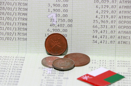 Four coins of Rial Omani money with mini Oman flag on the book bank. Concept of Saving money or...