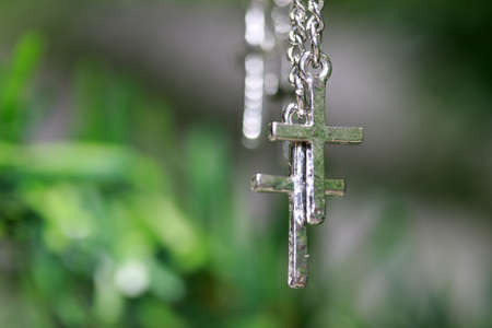 Metal crucifix bracelet hanging on the branches of tree. concept of faith and belief.の写真素材