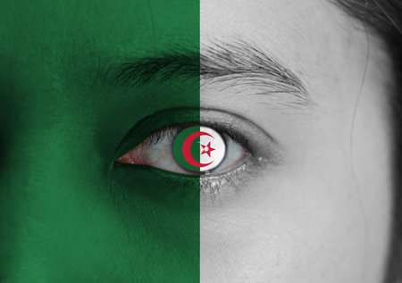 Human face painted Algeria flag with a red star and crescent on the center of eye or eyeball. Human...
