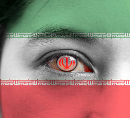 Human face painted Iran flag with National Emblem on the center of eye or eyeball. Human eye painted with flag of Iran.の写真素材