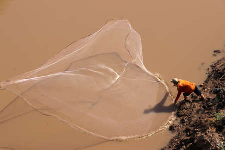 A fisherman throwing a net into the river for fishing.の写真素材