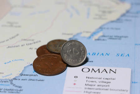 Heap of Rial Omani money coin put on the map. Concept of finance or currency or travel.の写真素材
