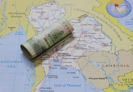 Rolled twenty baht banknote of Thailand put on the Thai map near Bangkok city. Concept of finance or currency or travel.の写真素材
