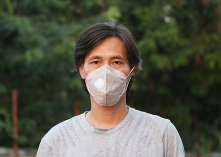 Masked Asian man prevent germs and wear grey shirt. Tiny Particle or virus corona or Covid 19...