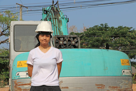 Female civil engineer or architect wear the white helmet and white T-shirt, Standing beside green...