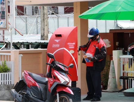 Pathumthani, Thailand - 29 May, 2020 : Thailand Post Officer unlocking the postbox to take the...