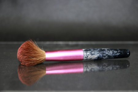 Makeup brush in pink color handle lay on the floor with a reflection. Accessories for makeup or...