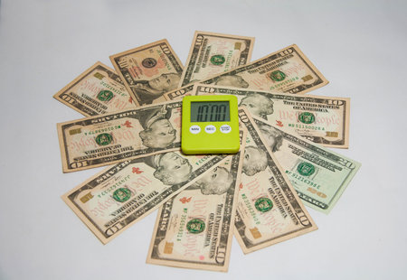 The concept of time is money. Green plastic square stopwatch on the circular US banknotes with white...